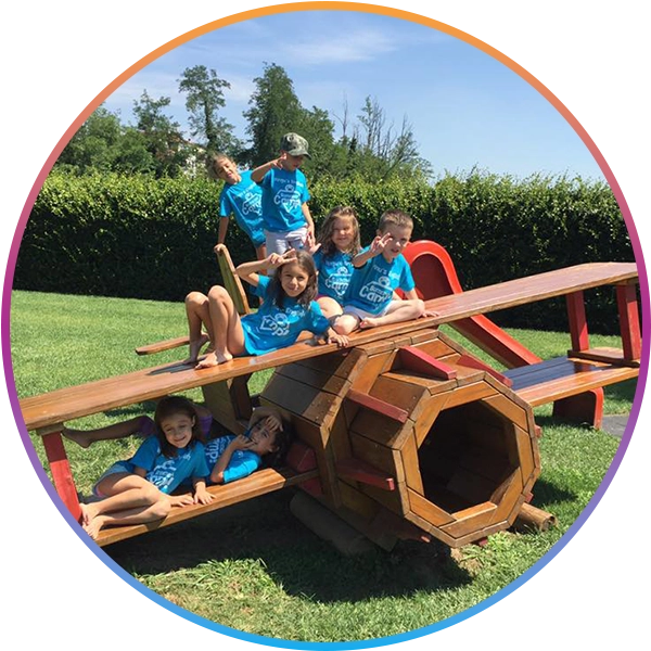 Children from a Pingu’s English holiday camp playing and having fun outside on a full-size airplane model in the sun.